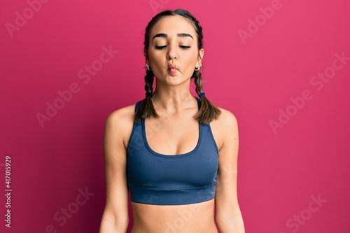 Young brunette girl wearing sportswear and braids making fish face with lips, crazy and comical gesture. funny expression. © Krakenimages.com