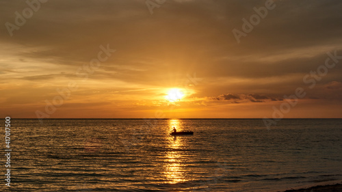 Cuba. Trinidad. Sunset in Ancon. A fisherman on a boat crosses the Sunny path © Минихан Сафин