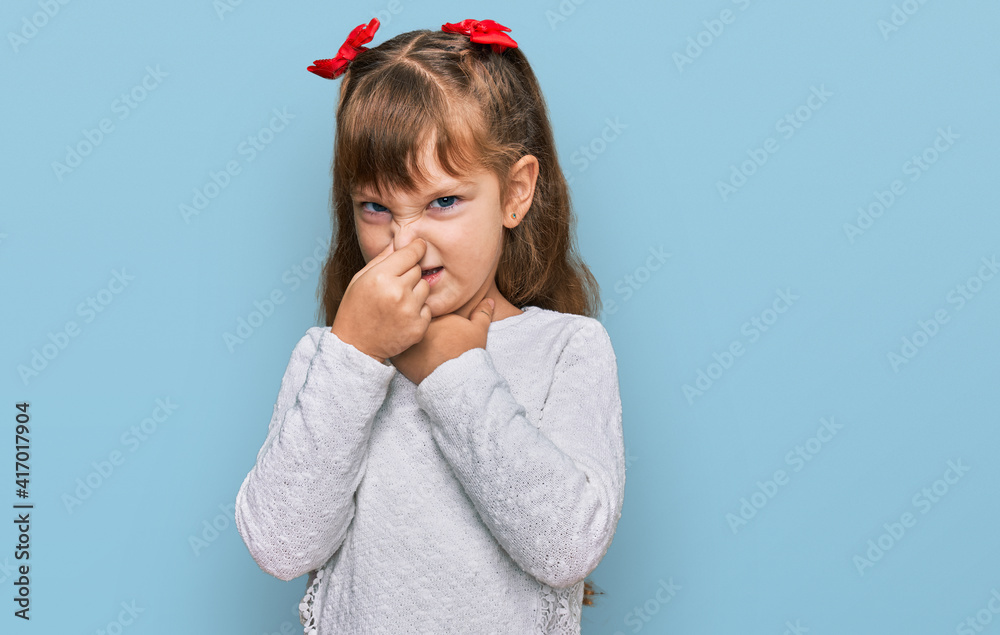 Little caucasian girl kid wearing casual clothes smelling something