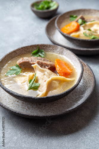 Traditional Jewish food dumplingd kreplach soup in gray bowl. photo