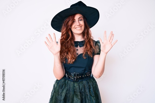 Young beautiful woman wearing witch halloween costume showing and pointing up with fingers number ten while smiling confident and happy. © Krakenimages.com