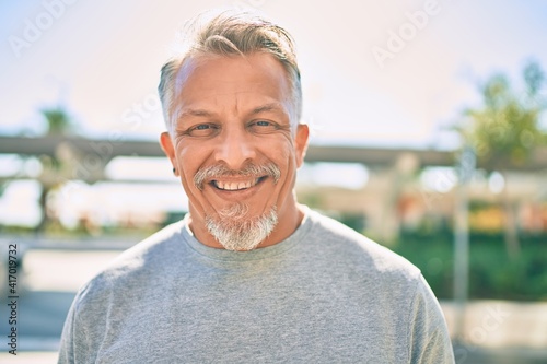Middle age hispanic grey-haired man smiling happy standing at the city.