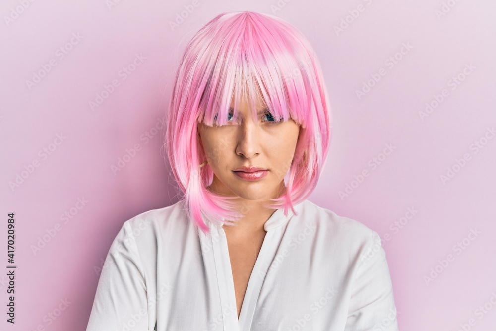 Young blonde woman wearing pink wig skeptic and nervous, disapproving expression on face with crossed arms. negative person. Young blonde woman wearing pink wig skeptic and nervous, disapproving expression on face with crossed arms. negative person.