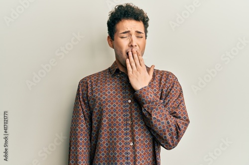 Handsome hispanic man wearing casual clothes bored yawning tired covering mouth with hand. restless and sleepiness.
