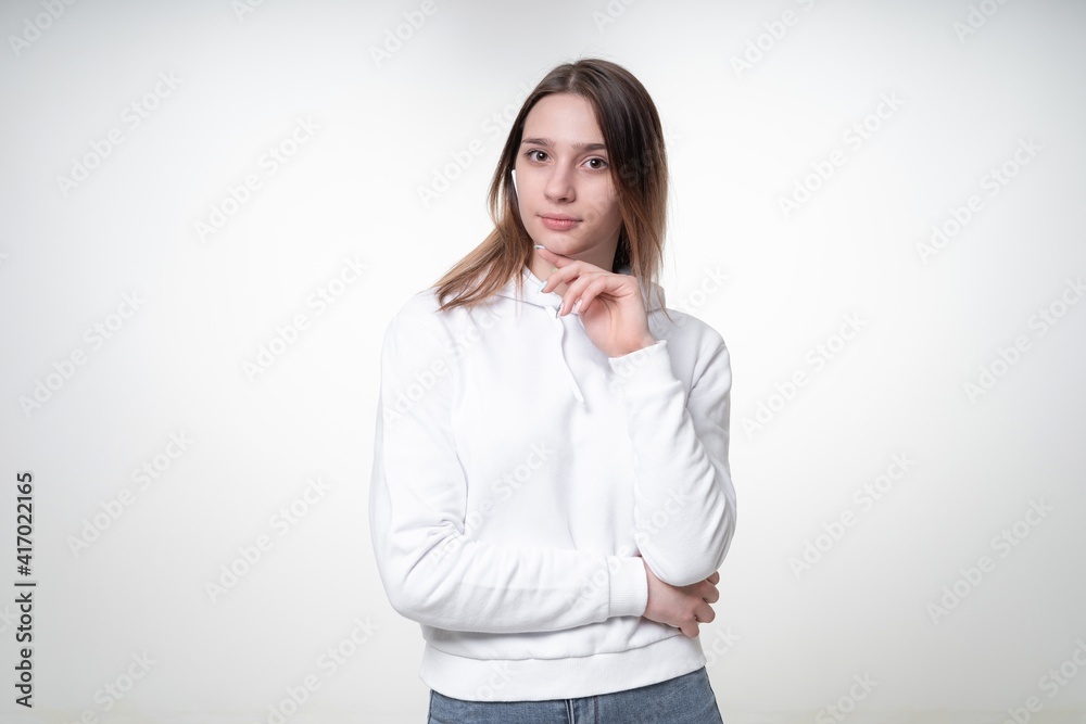 A cute young woman with fair hair is listening to music in her white wireless headphones, studio photo, white background A cute young woman with fair hair is listening to music in her white wireless headphones, studio photo, white background