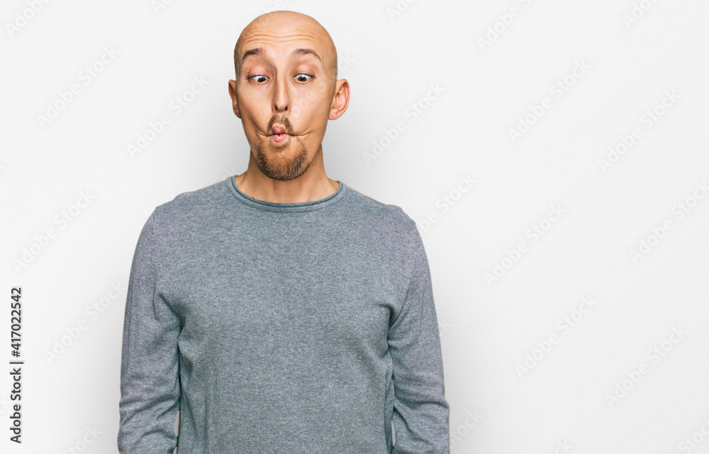 Bald man with beard wearing casual clothes making fish face with lips, crazy and comical gesture. funny expression. Bald man with beard wearing casual clothes making fish face with lips, crazy and comical gesture. funny expression.