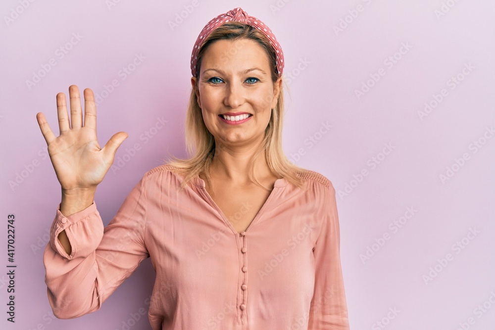 Middle age caucasian woman wearing casual clothes showing and pointing up with fingers number five while smiling confident and happy. Middle age caucasian woman wearing casual clothes showing and pointing up with fingers number five while smiling confident and happy.