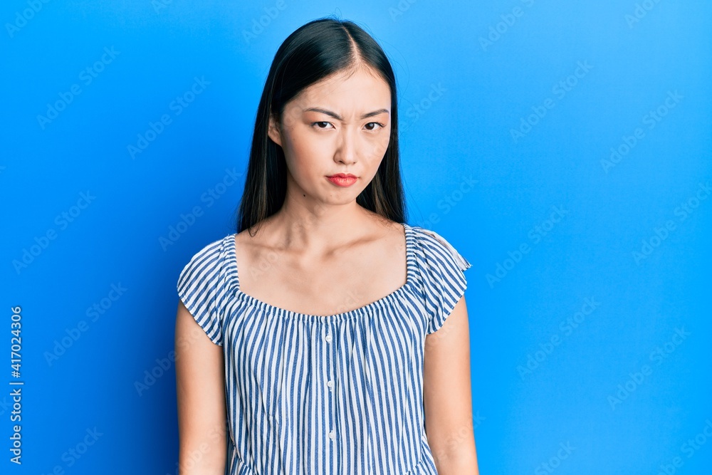 Young chinese woman wearing casual striped t-shirt skeptic and nervous, frowning upset because of problem. negative person. Young chinese woman wearing casual striped t-shirt skeptic and nervous, frowning upset because of problem. negative person.