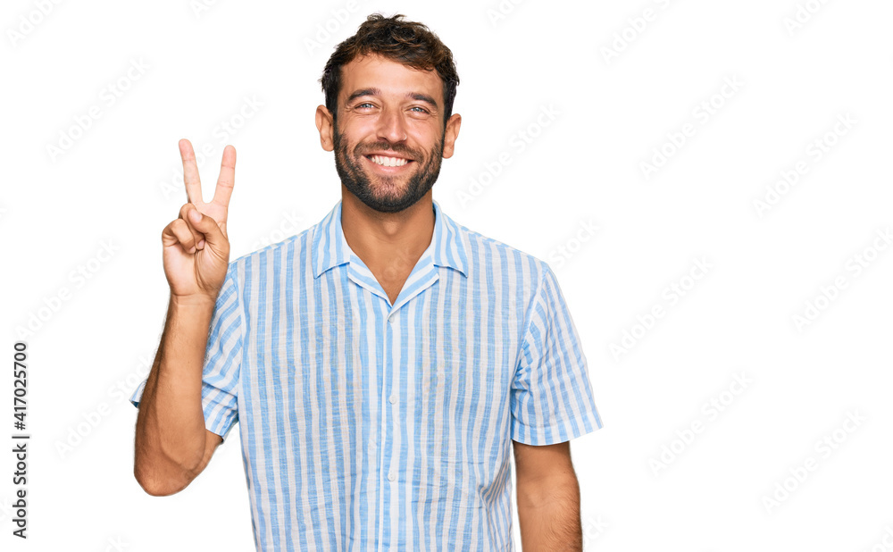 Handsome young man with beard wearing casual fresh shirt showing and pointing up with fingers number two while smiling confident and happy. Handsome young man with beard wearing casual fresh shirt showing and pointing up with fingers number two while smiling confident and happy.