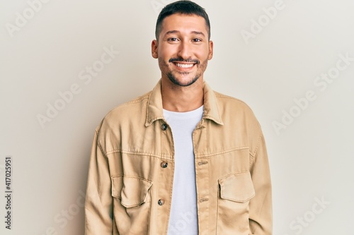 Handsome man with tattoos wearing casual brown denim jacket with a happy and cool smile on face. lucky person. © Krakenimages.com