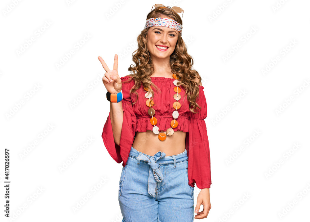 Young blonde girl wearing bohemian and hippie style smiling with happy face winking at the camera doing victory sign. number two.
