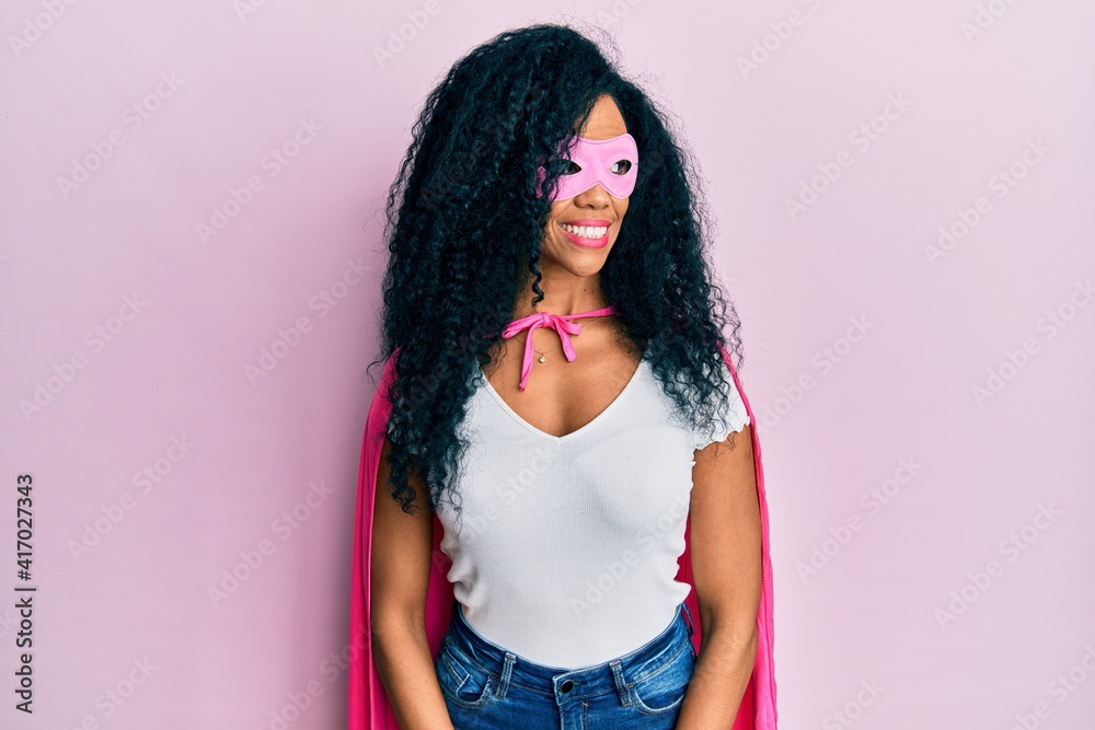 Middle age african american woman wearing super hero costume smiling looking to the side and staring away thinking. Middle age african american woman wearing super hero costume smiling looking to the side and staring away thinking.