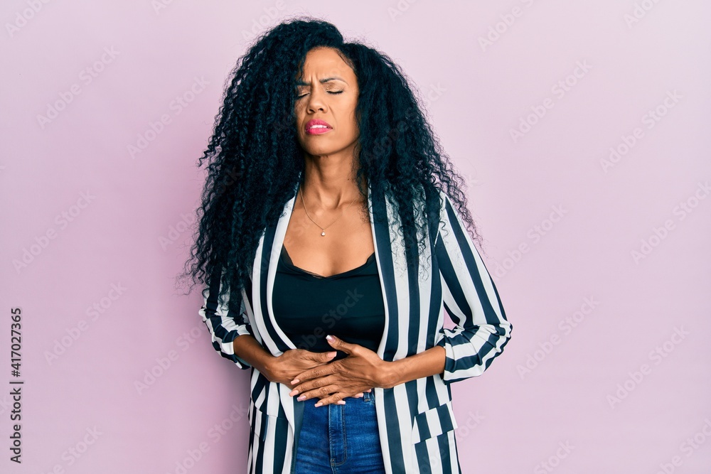 Middle age african american woman wearing casual clothes with hand on stomach because indigestion, painful illness feeling unwell. ache concept. Middle age african american woman wearing casual clothes with hand on stomach because indigestion, painful illness feeling unwell. ache concept.