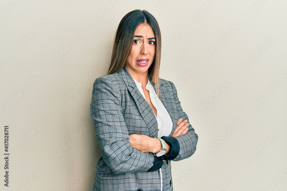 Young hispanic woman wearing business clothes with arms crossed gesture clueless and confused expression. doubt concept. Young hispanic woman wearing business clothes with arms crossed gesture clueless and confused expression. doubt concept.