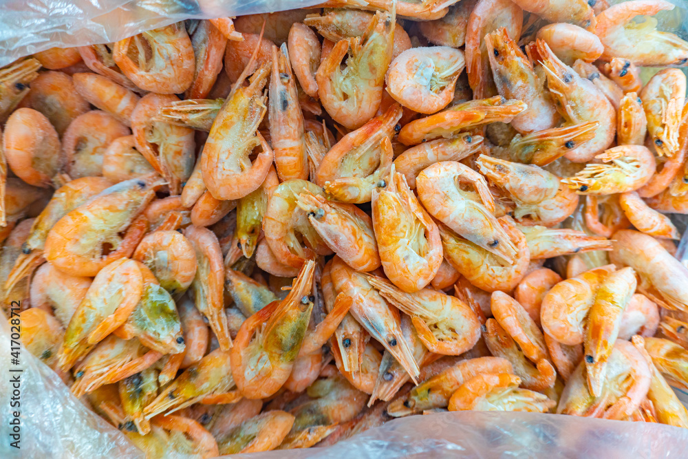 Pink fresh frozen shrimps with ice in a supermarket or fish shop. Fresh frozen prawns, delicacies, sea food concept. Uncooked seafood close up background Pink fresh frozen shrimps with ice in a supermarket or fish shop. Fresh frozen prawns, delicacies, sea food concept. Uncooked seafood close up background