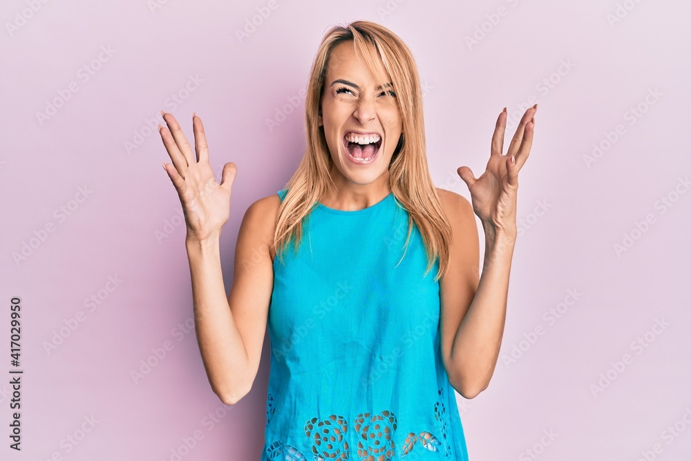 Beautiful blonde woman wearing casual clothes celebrating mad and crazy for success with arms raised and closed eyes screaming excited. winner concept Beautiful blonde woman wearing casual clothes celebrating mad and crazy for success with arms raised and closed eyes screaming excited. winner concept
