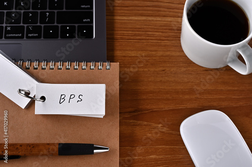 On the desk there is a laptop  a cup of coffee  and a word book with the word BPS written on it. It was an abbreviation for the financial term book-value per share.