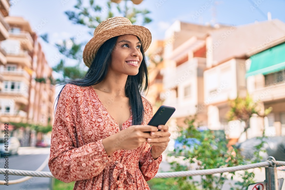 Fototapeta premium Young african american tourist woman on vacation smiling happy using smartphone at the city.