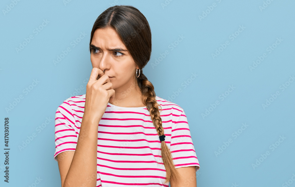 Young hispanic woman wearing casual clothes looking stressed and nervous with hands on mouth biting nails. anxiety problem. Young hispanic woman wearing casual clothes looking stressed and nervous with hands on mouth biting nails. anxiety problem.