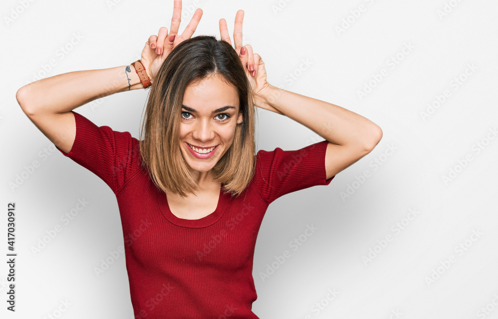 Fototapeta premium Young blonde girl wearing casual clothes posing funny and crazy with fingers on head as bunny ears, smiling cheerful