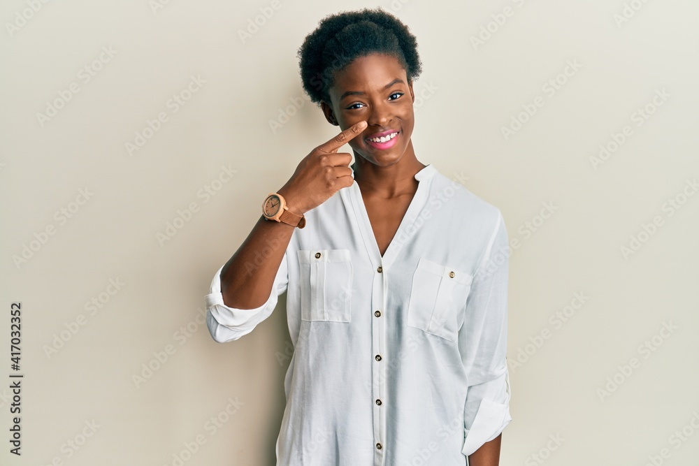 Young african american girl wearing casual clothes pointing with hand finger to face and nose, smiling cheerful. beauty concept Young african american girl wearing casual clothes pointing with hand finger to face and nose, smiling cheerful. beauty concept