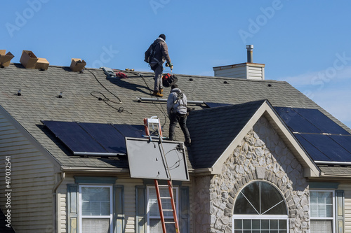 Technician workers installing alternative energy photovoltaic solar panels on roof