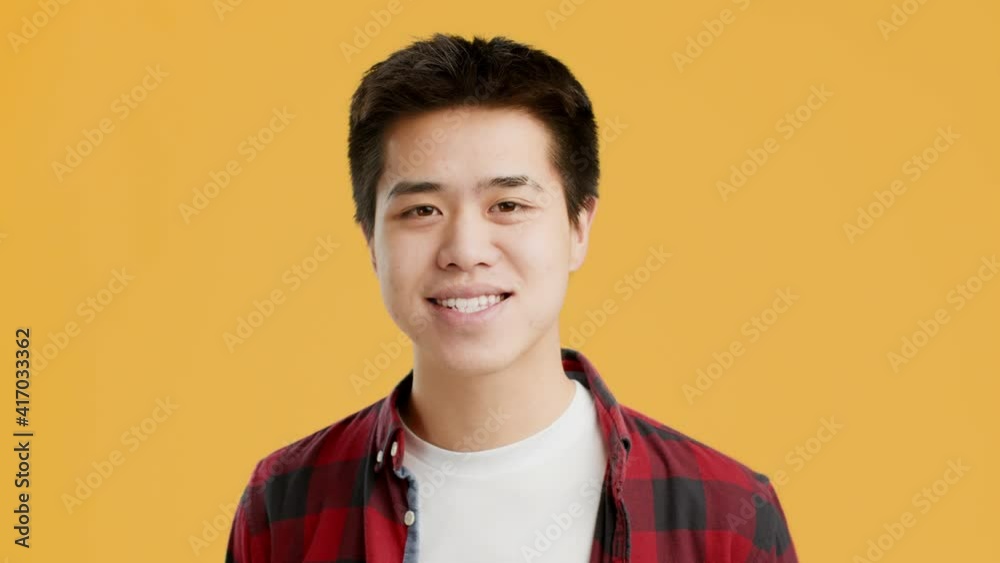 Joyful Asian Man Waving Hello Posing Standing On Yellow Background Joyful Asian Man Waving Hello Posing Standing On Yellow Background
