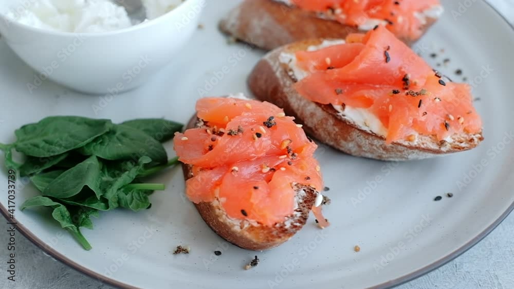 Delicious toast with salmon and cheese cream on a white plate whit spinach, close-up.