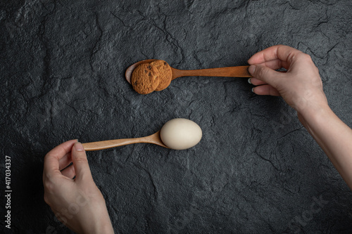 Female hands holding spoons of egg and cookie