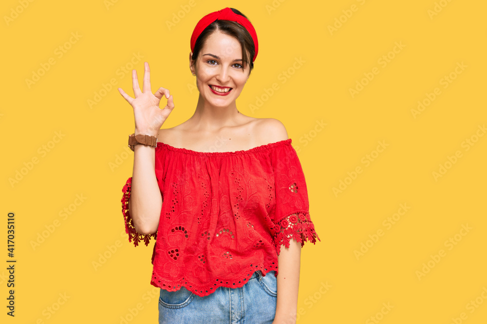 Young brunette woman with short hair wearing casual summer clothes and diadem smiling positive doing ok sign with hand and fingers. successful expression.