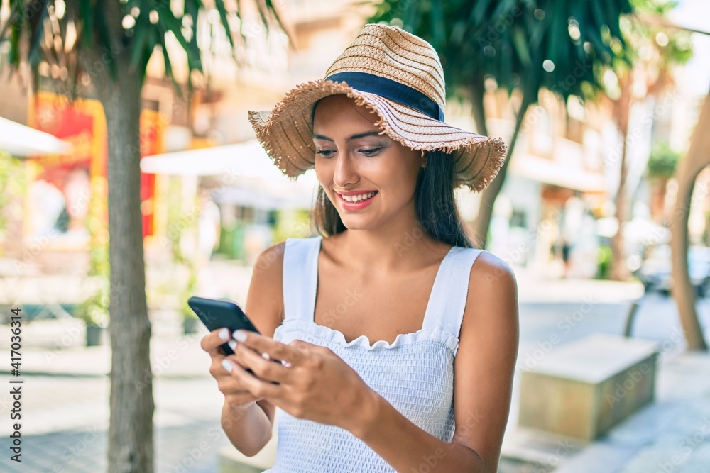 Young latin girl wearing summer style using smartphone at street of city.