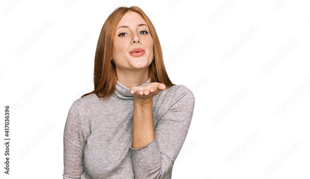 Young irish woman wearing casual clothes looking at the camera blowing a kiss with hand on air being lovely and sexy. love expression. Young irish woman wearing casual clothes looking at the camera blowing a kiss with hand on air being lovely and sexy. love expression.