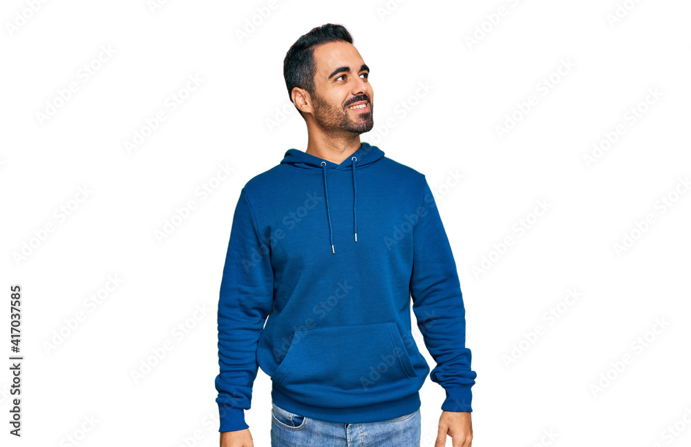 Young hispanic man wearing casual clothes looking away to side with smile on face, natural expression. laughing confident. Young hispanic man wearing casual clothes looking away to side with smile on face, natural expression. laughing confident.