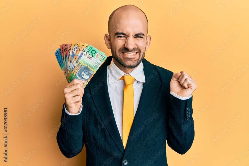 Young hispanic business man holding canadian dollars screaming proud, celebrating victory and success very excited with raised arm Young hispanic business man holding canadian dollars screaming proud, celebrating victory and success very excited with raised arm
