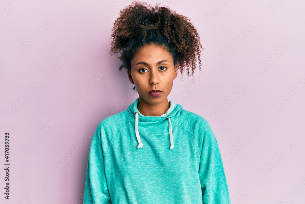 Beautiful african american woman with afro hair wearing casual sweatshirt with serious expression on face. simple and natural looking at the camera. Beautiful african american woman with afro hair wearing casual sweatshirt with serious expression on face. simple and natural looking at the camera.