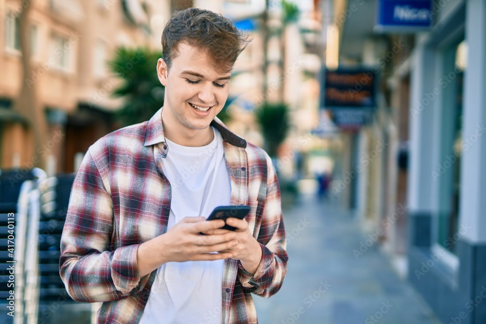 Young caucasian man smiling happy using smartphone at the city. Young caucasian man smiling happy using smartphone at the city.