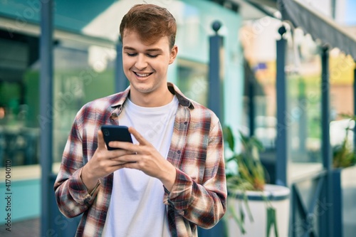 Young caucasian man smiling happy using smartphone at the city.