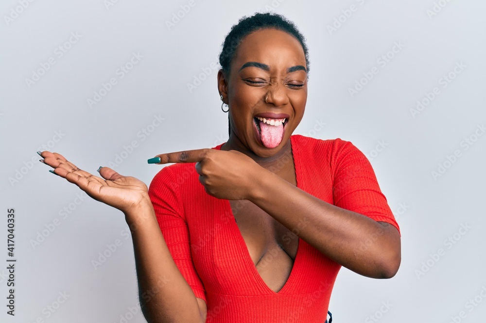 Φωτογραφία Young african american woman pointing hand with finger sticking tongue out happy with funny expression
