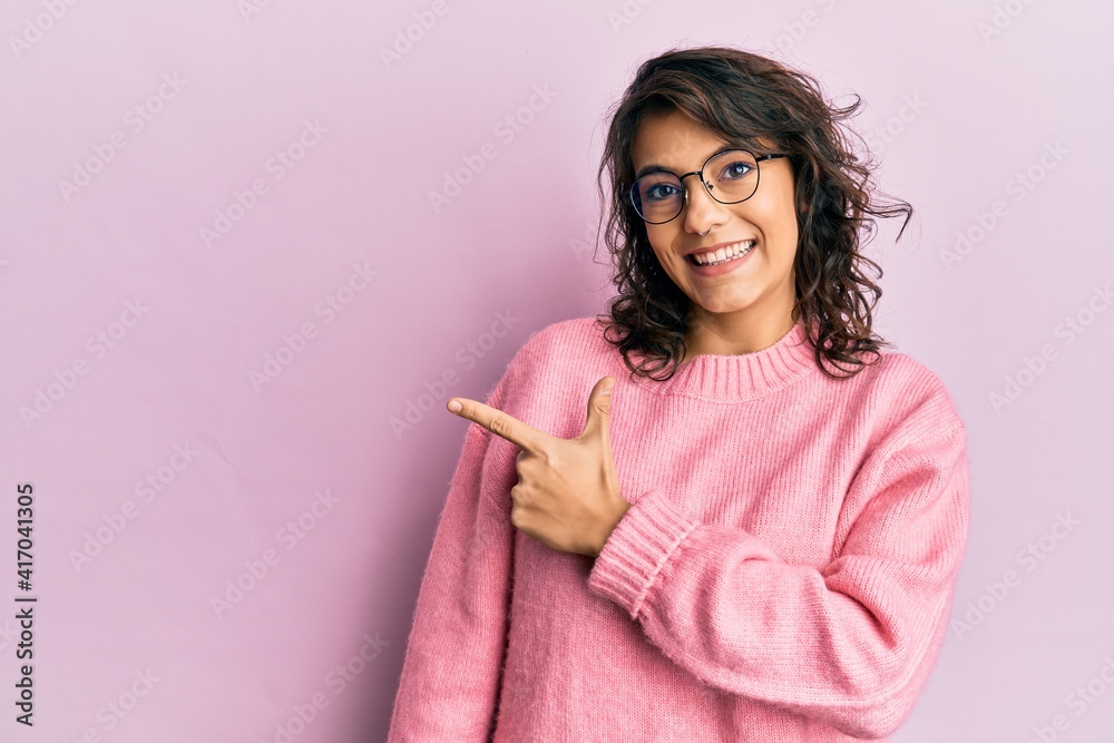 Young hispanic woman wearing casual clothes and glasses smiling cheerful pointing with hand and finger up to the side Young hispanic woman wearing casual clothes and glasses smiling cheerful pointing with hand and finger up to the side