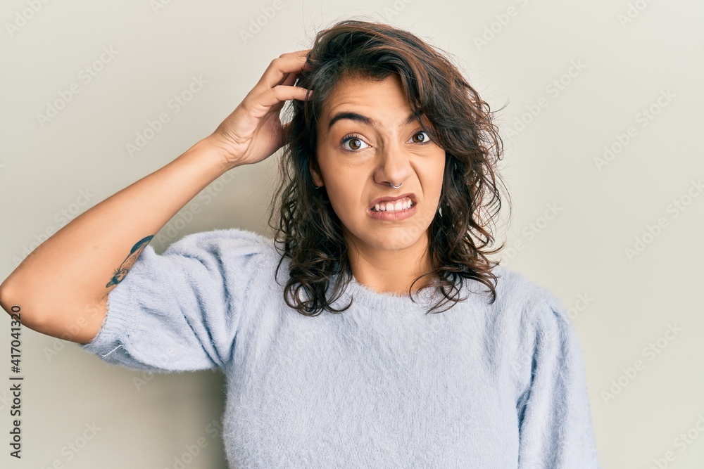 Young hispanic woman wearing casual winter sweater confuse and wonder about question. uncertain with doubt, thinking with hand on head. pensive concept. Young hispanic woman wearing casual winter sweater confuse and wonder about question. uncertain with doubt, thinking with hand on head. pensive concept.