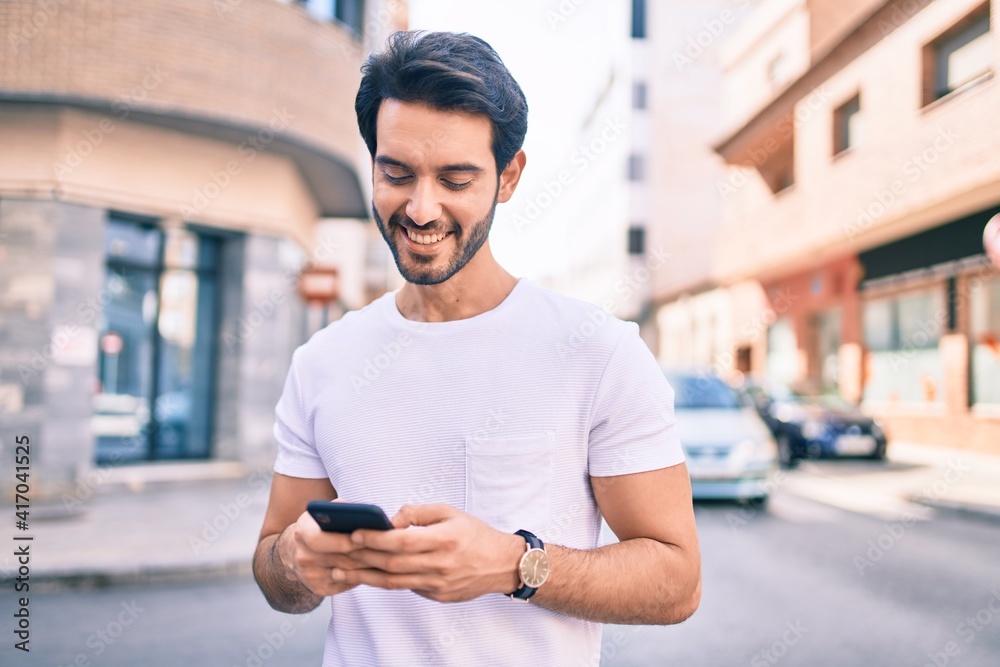 Young hispanic man smiling happy using smartphone at city. Young hispanic man smiling happy using smartphone at city.