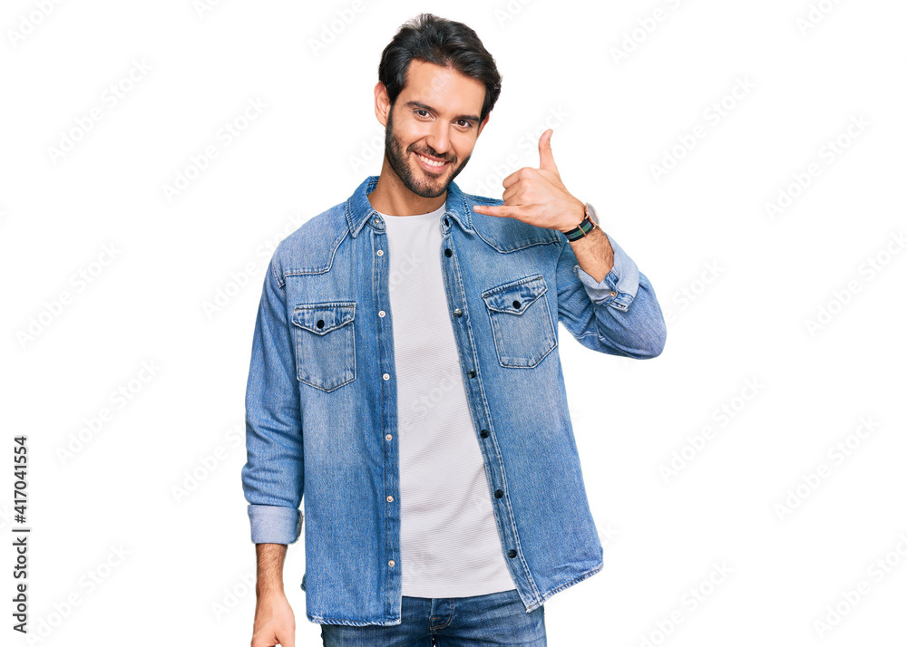 Young hispanic man wearing casual clothes smiling doing phone gesture with hand and fingers like talking on the telephone. communicating concepts. Young hispanic man wearing casual clothes smiling doing phone gesture with hand and fingers like talking on the telephone. communicating concepts.