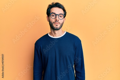 Young hispanic man wearing casual clothes and glasses with serious expression on face. simple and natural looking at the camera. © Krakenimages.com