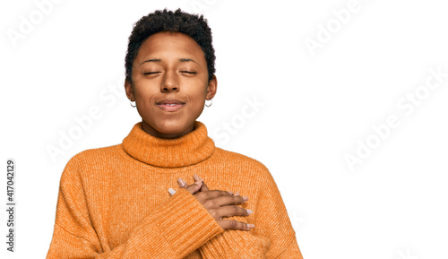 Young african american woman wearing casual clothes smiling with hands on chest with closed eyes and grateful gesture on face. health concept.