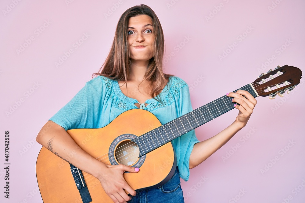 Beautiful caucasian woman playing classical guitar puffing cheeks with funny face. mouth inflated with air, catching air. Beautiful caucasian woman playing classical guitar puffing cheeks with funny face. mouth inflated with air, catching air.