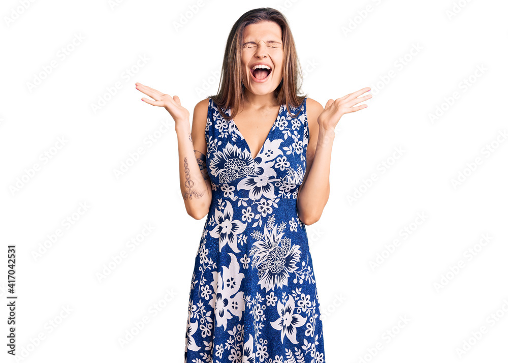 Beautiful caucasian woman wearing summer dress celebrating mad and crazy for success with arms raised and closed eyes screaming excited. winner concept Beautiful caucasian woman wearing summer dress celebrating mad and crazy for success with arms raised and closed eyes screaming excited. winner concept
