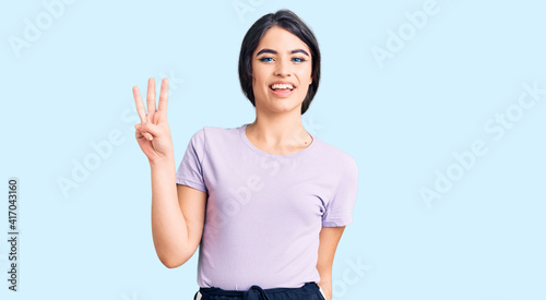Brunette teenager girl wearing casual clothes showing and pointing up with fingers number three while smiling confident and happy.