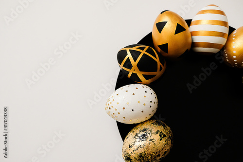 Stylish Easter golden decorated eggs on black plate isolated on white background. Trendy flat lay easter. Happy Easter card with copy space for text. Minimal easter concept. photo