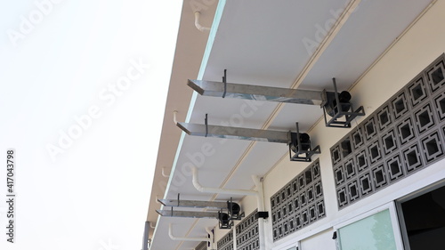 Ventilation ducts under the eaves. Several silver pipes suck the air in the canteen kitchen to provide ventilation on the white sky background with a copy area. Selective focus