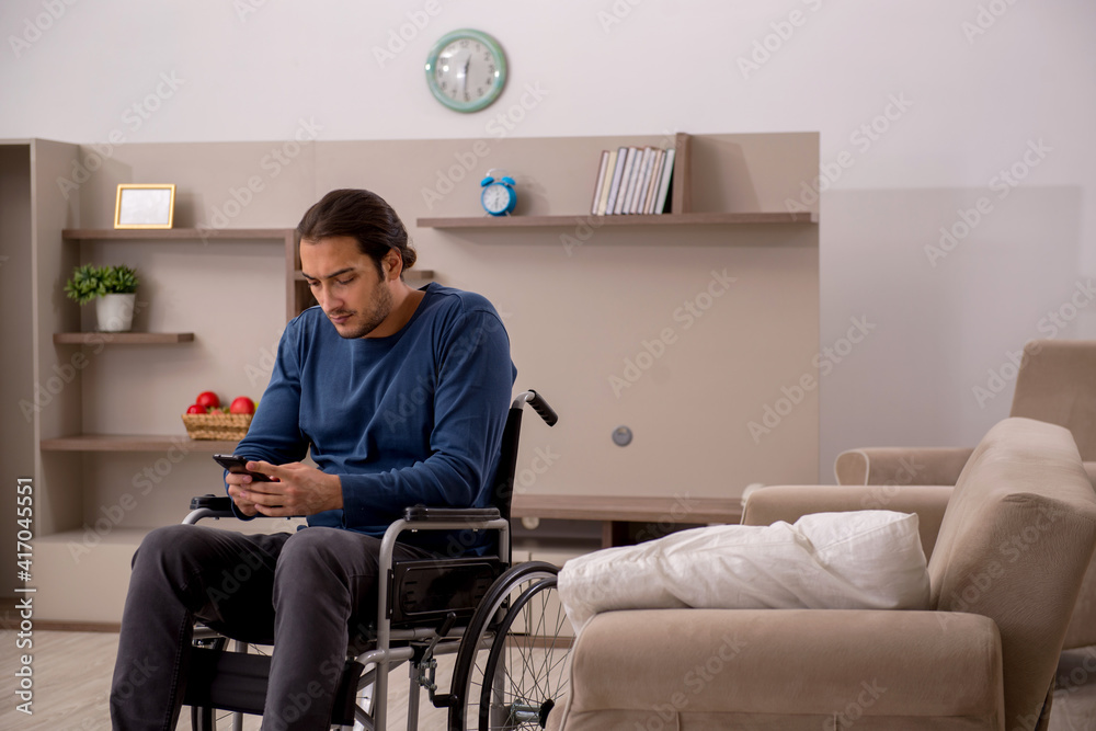 Young man in wheel-chair suffering at home Young man in wheel-chair suffering at home